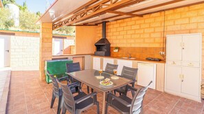 Ein Außenbereich mit Küchenzeile, einem Tisch, Stühlen, einem Grill und einer Ziegelwand.