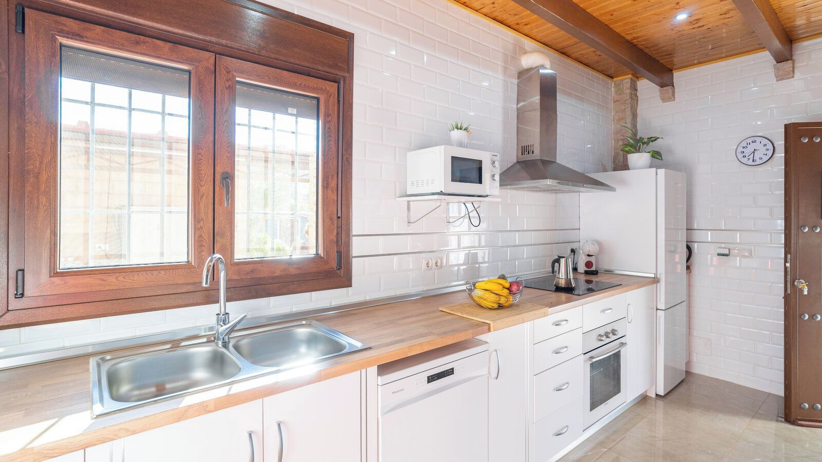 A modern kitchen with white cabinets, a stainless steel sink, a microwave, and a stove.