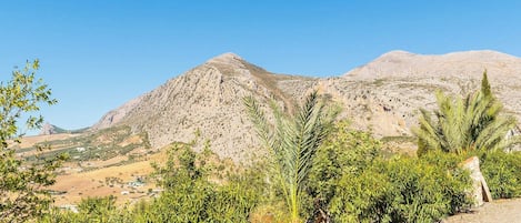 A mountainous landscape with sparse vegetation and a clear sky.