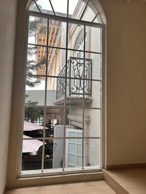 Una ventana con una reja metálica decorativa, vista de un edificio con balcones y suelo de baldosas.