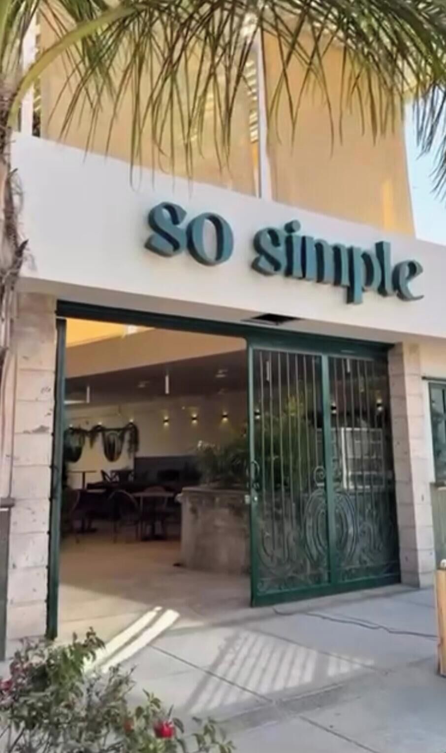 A storefront with a sign reading 'SO simple' and a green metal gate.