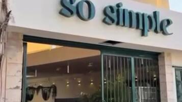 A storefront with a sign reading 'SO simple' and a green metal gate.