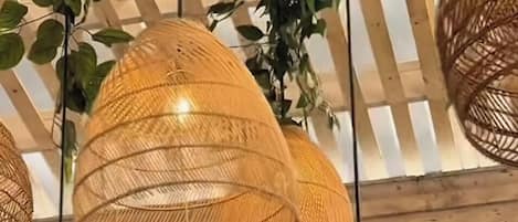 Teto com várias luminárias trançadas e folhagem pendente.