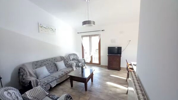 A living room with a sofa, coffee table, and a television.