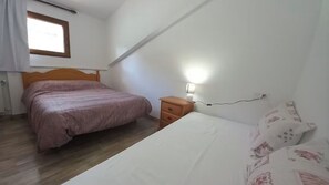 Makuuhuone, jossa on sänky, yöpöytä, lamppu ja ikkuna.
