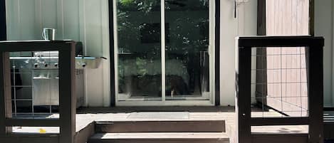 Una terraza de madera con puerta corrediza de vidrio que da a un espacio cubierto.