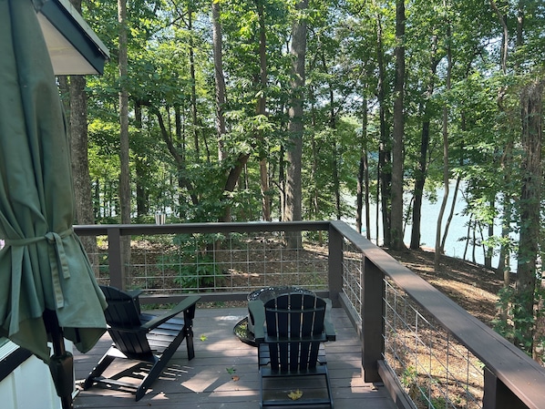 A deck with outdoor furniture, a railing, and a view of a forested area.