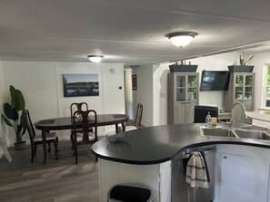 A compact kitchen with a dining area, a built-in refrigerator, and a flat-screen TV mounted on the wall. - Adorable 3-bedroom experience on Lake Hartwell with great access to nature (Lavonia)