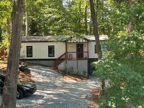 A cabin with a gravel driveway, a staircase, and a car parked nearby. - Adorable 3-bedroom experience on Lake Hartwell with great access to nature (Lavonia)