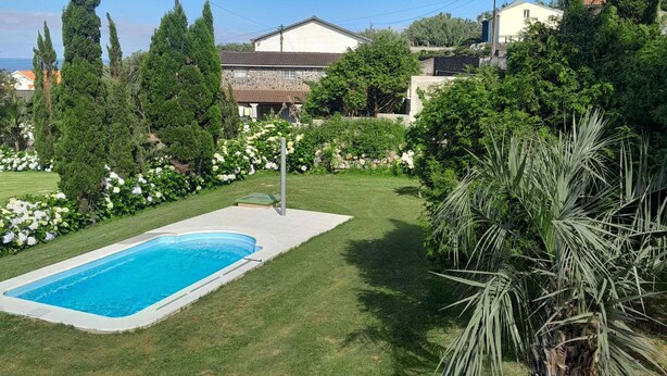 Una propiedad residencial con piscina, césped cuidado y varios árboles.