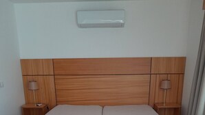 Una cama doble con cabecera de madera, dos mesitas de noche con lámparas y un interruptor de luz en la pared.