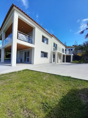 Un edificio moderno de dos pisos con techo plano, ventanas amplias y un balcón.