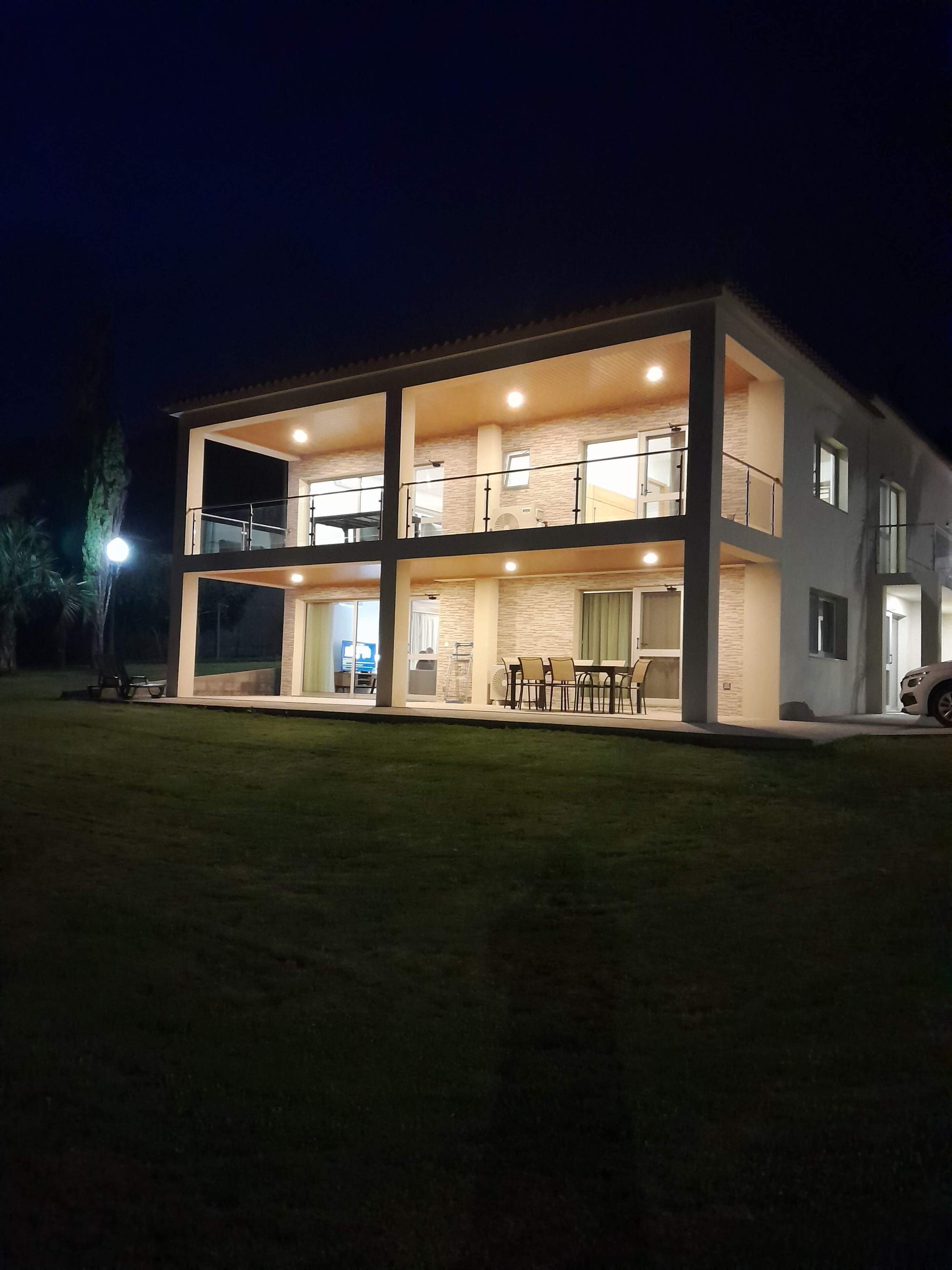 Una casa moderna de dos pisos con balcón, comedor y un coche estacionado afuera.