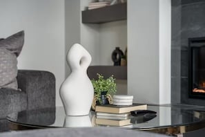 A modern living room with a glass coffee table, a white abstract sculpture, a small potted plant, a stack of books, and a remote control. - ATV Parking + Private spa + Waterpark Hurricane UT (Hurricane)