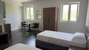 Une chambre à coucher avec un lit, un bureau et une chaise. On y trouve également une armoire et une fenêtre donnant sur un paysage verdoyant.