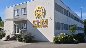 Un edificio con un cartel que dice 'CHM BOARDING' y una escalera que lleva a la entrada.