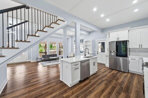 A modern kitchen with white cabinetry, a stainless steel refrigerator, and a wooden staircase. - Modern 3-Bedroom Home in Downtown Raleigh - Close to EVERYTHING (Raleigh)