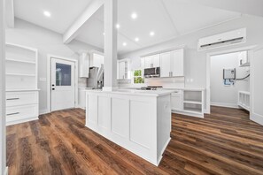A modern kitchen with white cabinetry, a central island, and a built-in oven. - Modern 3-Bedroom Home in Downtown Raleigh - Close to EVERYTHING (Raleigh)