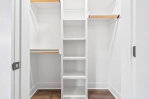 A white closet with multiple shelves and wooden rods.