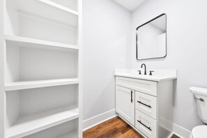 A white bathroom with a white vanity, a mirror, and a toilet. - Modern 3-Bedroom Home in Downtown Raleigh - Close to EVERYTHING (Raleigh)