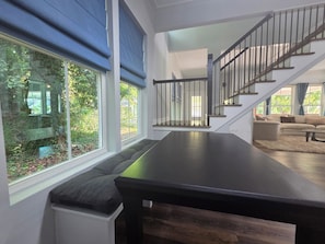A modern living room with a dark wooden table, a sofa, and a staircase with black railings.
