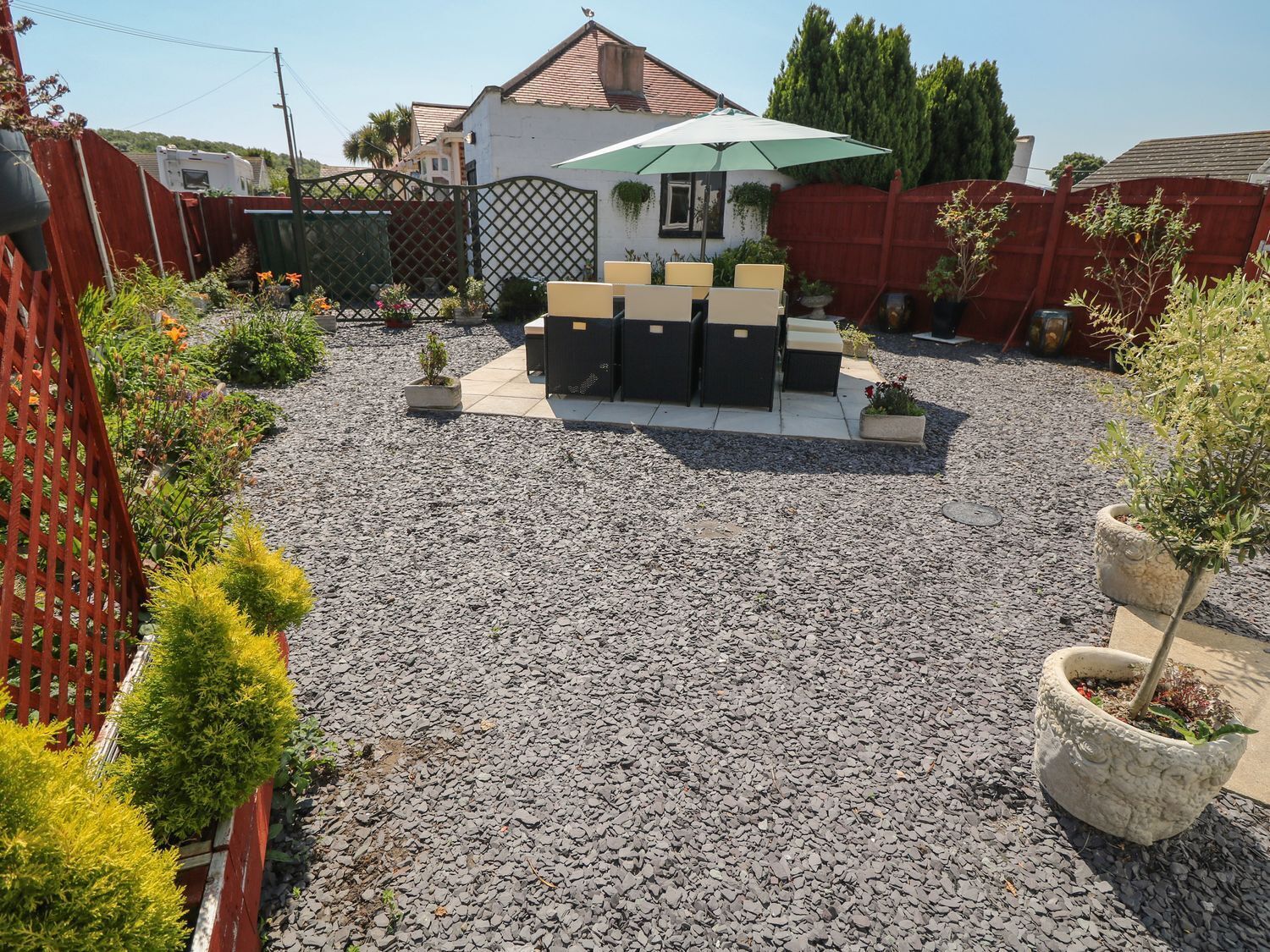 A backyard with a patio area, a small garden, and a house in the background.