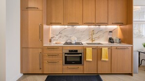 Una cocina con armarios de madera, un horno Bosch, un lavamanos con grifo dorado y un salpicadero de mármol.