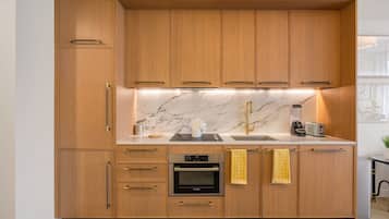 Cozinha com armários de madeira, forno Bosch, pia com torneira dourada e painel de fundo em mármore.