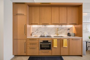 Cozinha com armários de madeira, forno Bosch, pia com torneira dourada e painel de fundo em mármore.