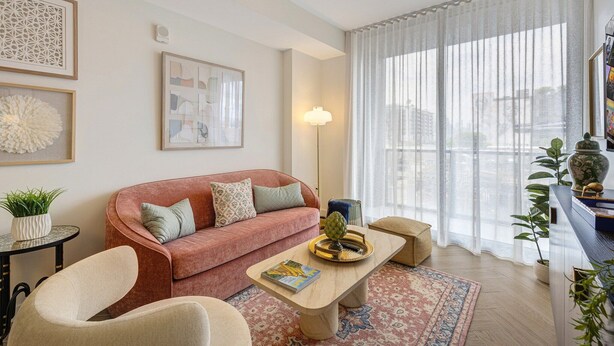 Una sala de estar moderna con un sofá, sillones, una mesita de centro y un ventanal con cortinas de gasa.