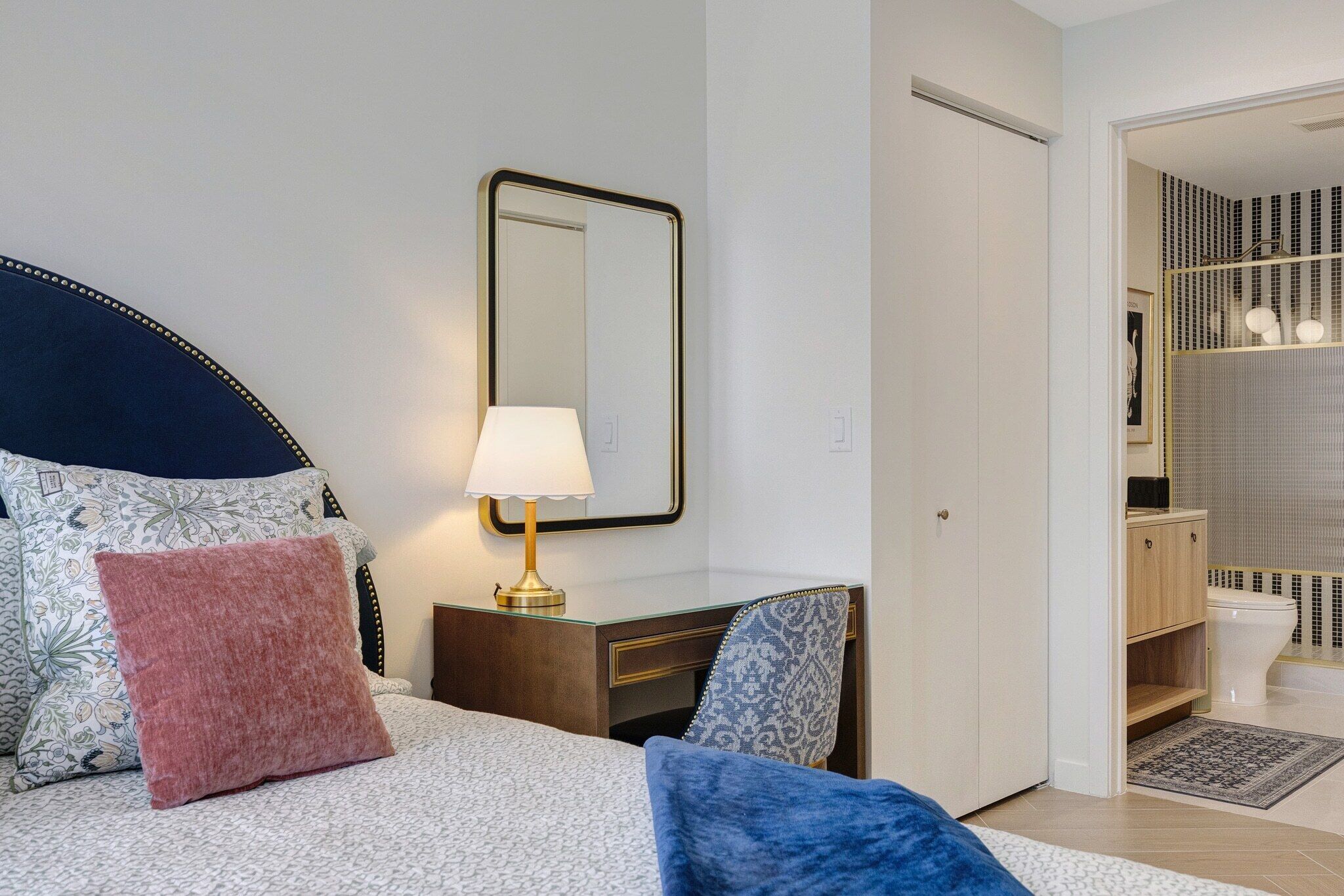 Ein Hotelzimmer mit Bett, Nachttisch, Lampe und Spiegel.