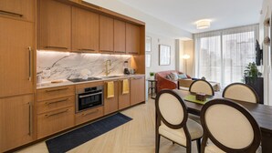 Una cocina moderna con armarios de madera, encimera de mármol y comedor con mesa y sillas.