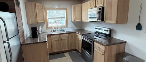Una cocina con armarios de madera, un refrigerador de acero inoxidable, un microondas y una estufa.