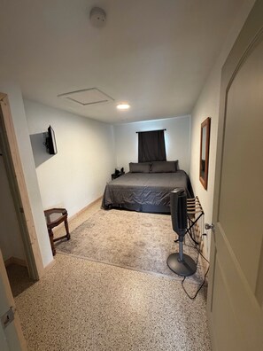 Ein kleines, gemütliches Schlafzimmer mit einem Einzelbett, einem Nachttisch, einem Spiegel und einem Standheizgerät.