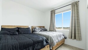 A bedroom with two wooden beds, a window with curtains, and a view of the outdoors. - Aurora Modern Retreat (Aurora)