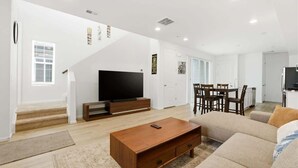 A living room with a TV, sofa, coffee table, and a staircase leading to another room. - Aurora Modern Retreat (Aurora)