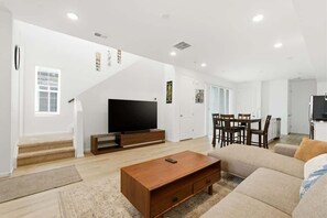 Ein Wohnzimmer mit Fernseher, Sofa, Couchtisch und einer Treppe zu einem anderen Raum.