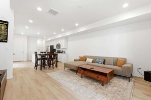 Ein zeitgemäßer Wohnraum mit Essbereich, Sofa und einer Küche im Hintergrund.