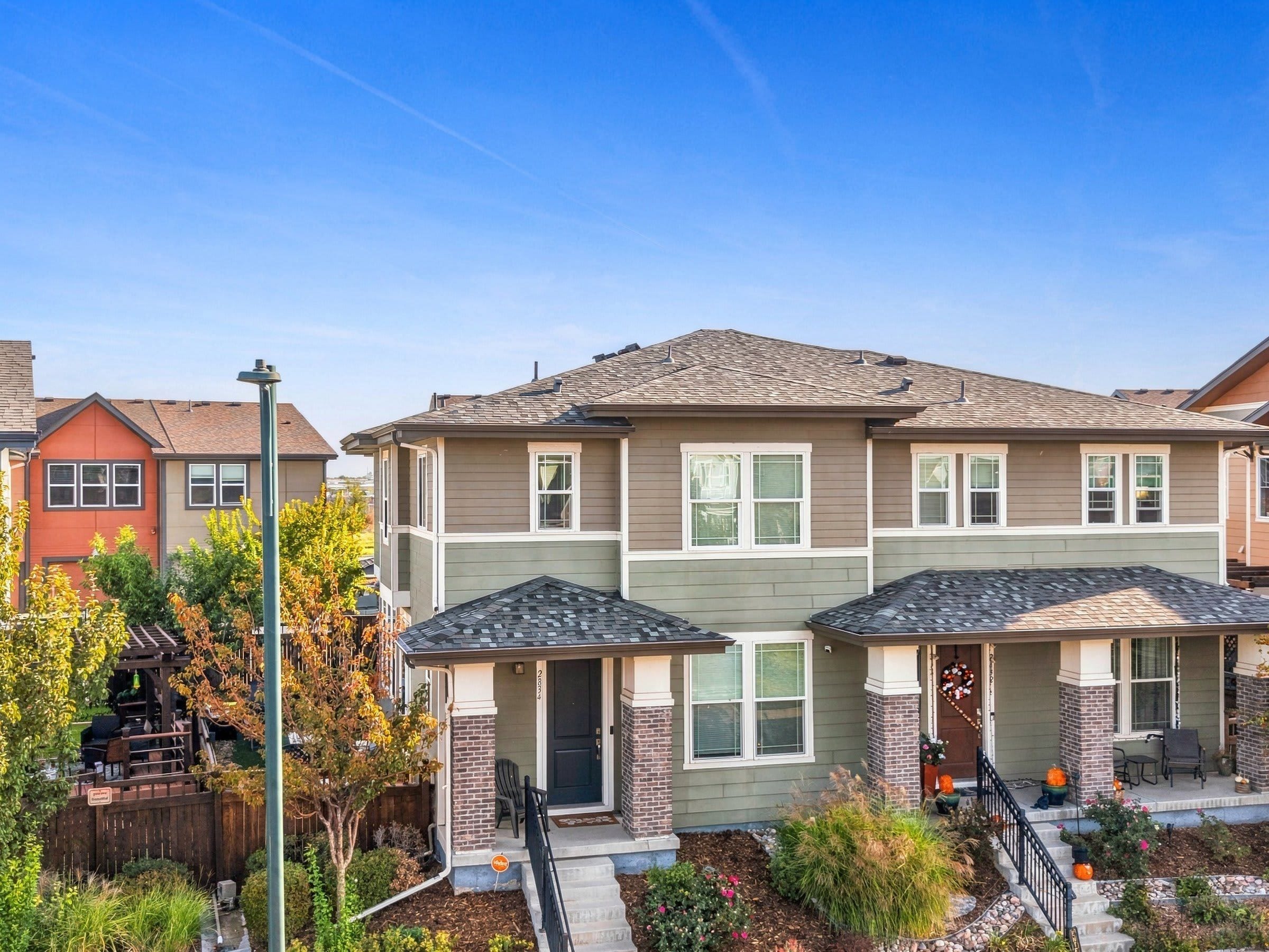 A residential building with a two-story structure, a front porch, and a landscaped garden.