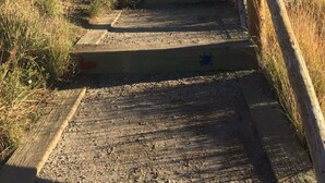 Un ensemble d’escaliers extérieurs en bois menant vers le haut, avec une main courante en bois sur le côté droit.