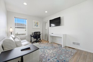 A modern living room with a white sofa, a desk, a chair, a TV, and a patterned rug. - Central Park Denver 3BR and Loft Near Anschutz  DIA (Denver)