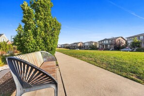 A residential street with houses, a sidewalk, and a bench. - Central Park Denver 3BR and Loft Near Anschutz  DIA (Denver)