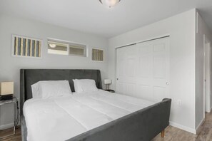 Ein Schlafzimmer mit Bett, Nachttisch, Lampe und Tür.