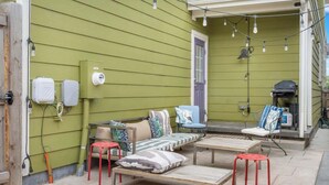 A green house exterior with outdoor furniture, a barbecue grill, and utility meters. - Charming Central Park Denver Single Family Home (Denver)