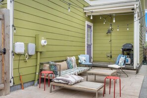 A green house exterior with outdoor furniture, a barbecue grill, and utility meters. - Charming Central Park Denver Single Family Home (Denver)
