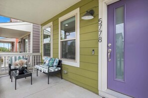 A porch with a bench and a table, a purple door, and a green wall. - Charming Central Park Denver Single Family Home (Denver)