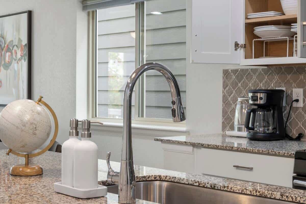 A kitchen with a stainless steel sink, a coffee maker, and a globe on the counter.