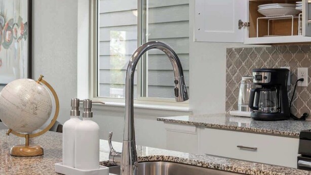 A kitchen with a stainless steel sink, a coffee maker, and a globe on the counter. - Charming Central Park Denver Single Family Home (Denver)