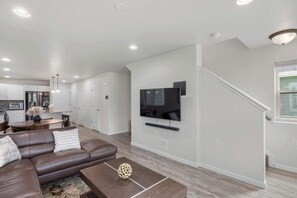 Ein modernes Wohnzimmer mit einem braunen Ledersofa, einem Couchtisch und einem flachbildfernseher, der an der Wand montiert ist.