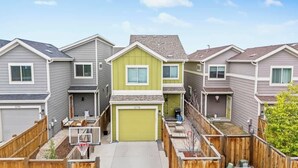 A row of townhouses with individual garages, a basketball hoop, and a small fenced yard. - Charming Central Park Denver Single Family Home (Denver)